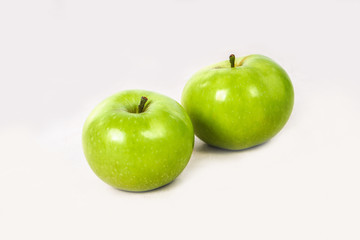 Two lovely green juicy apples on a white isolated background. Vegetarian food. Stock photo