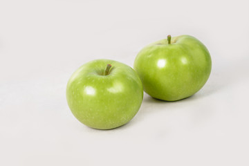 Two lovely green juicy apples on a white isolated background. Vegetarian food. Stock photo