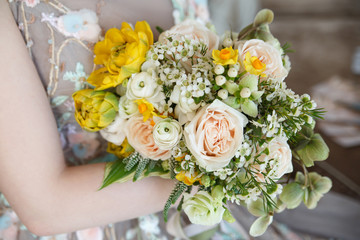 The bride holds a delicate spring wedding bouquet in her hand.