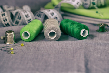 Sewing accessories in green and purple on a gray fabric background