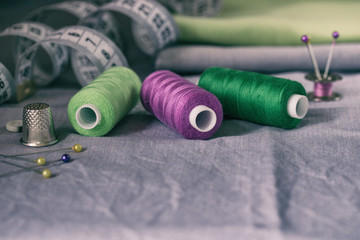 Sewing accessories in green and purple on a gray fabric background