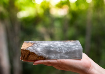 Hand holding casting epoxy resin Stabilizing burl Afzelia wood color abstract art background for blanks