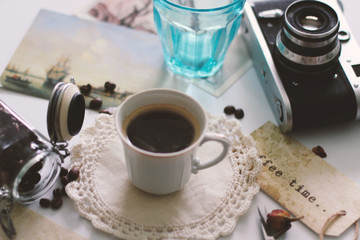 A Cup of coffee is on the table, next is a retro camera