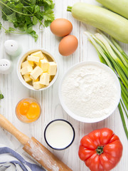 Ingredients for cooking quiche with vegetables (squash, tomatoes, cheese, herbs, green onions), open tart, French cuisine, traditional pastries