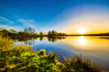 Lake with trees at sunset on a beautiful summer evening