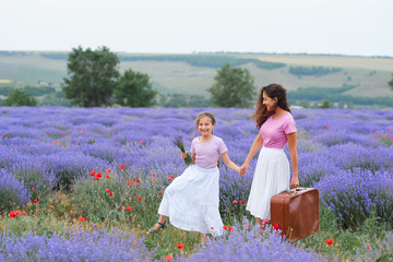 young woman and girl are walking through the lavender flower field, beautiful summer landscape