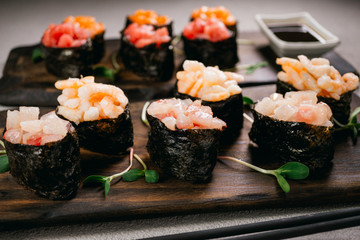Food blog and culinary. Seafood delicatessen gunkan maki sushi rolls on wooden plates. Different gourmet snacks. Luxury lifestyle, expensive meals, restaurant menu