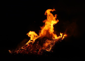 Large bonfire, burning and glowing with soft flames, sparkles flying agains the dark sky. Glowing wood silhouettes. Walpurgis night, traditional witch burning and spring welcoming ritual. 30 April.