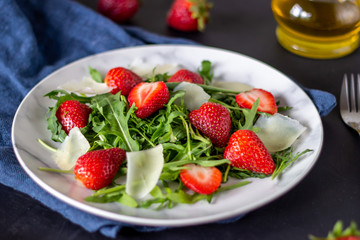 Salad of strawberries, arugula and cheese on a dark background. Dietary food.