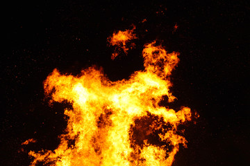 Large bonfire, burning and glowing with soft flames, sparkles flying agains the dark sky. Walpurgis night, traditional witch burning and spring welcoming ritual in the Czech Republic, April 30.