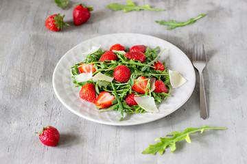 Salad of strawberries, arugula and cheese on a grey background. Dietary food.