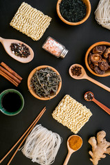 Chinese and Japanese food cooking with ginger, spices and noodles on black background top view geometric pattern