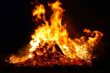 Large bonfire, burning and glowing with soft flames, sparkles flying agains the dark sky. Glowing...