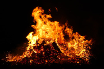 Large bonfire, burning and glowing with soft flames, sparkles flying agains the dark sky. Glowing wood silhouettes. Walpurgis night, traditional witch burning and spring welcoming ritual. 30 April.