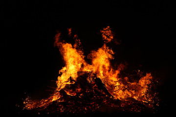 Large bonfire, burning and glowing with soft flames, sparkles flying agains the dark sky. Glowing wood silhouettes. Walpurgis night, traditional witch burning and spring welcoming ritual. 30 April.