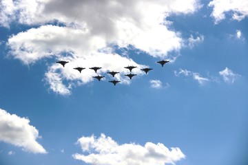 A group of ten aircraft in a blue sky with white clouds, selective focus