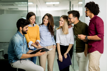 Multiethnic group of young people standing in the modern office and brainstorming