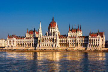 Fototapeta premium Hungary, Budapest: Famous Hungarian Parliament Building at sunny afternoon in the city center of the Hungarian capital with Donau Danube water, blue sky in background - travel architecture politics