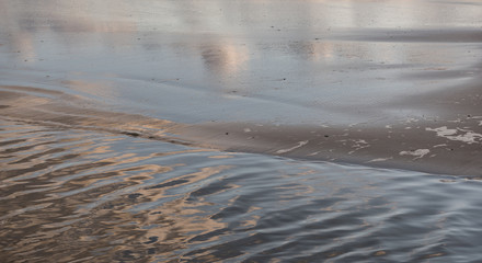 small waves at low tide on sandy beach