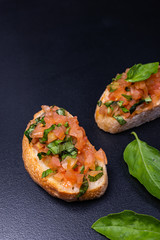 Delicious Italian antipasti bruschetta on black background. Close-up.