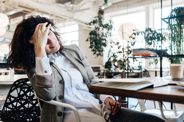 Fototapeta premium Tired happy business woman wearing suit sitting and resting in city cafe with notepad