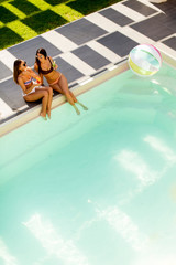 Two pretty young women relaxing by the swimming pool