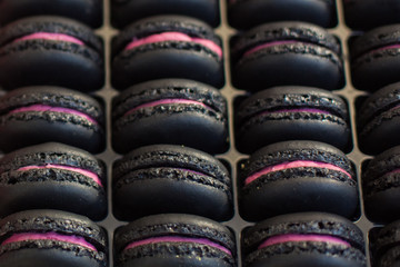 Black and pink colorful french macarons dessert with vintage pastel tones, close up. Tasty sweet...