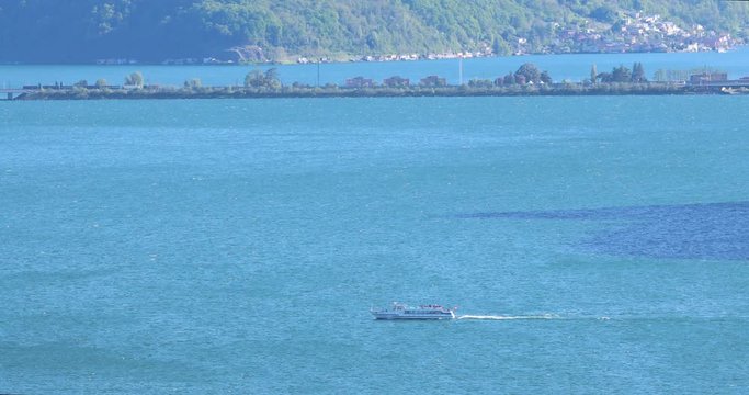 Wide long shot of a tourist ferry crossing a lake immersed in a mountain environment. Tourism concept