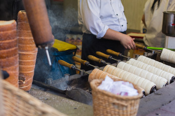 Making Trdelnik or Trdlo or Kurtosh Kalach being baked in a street bakery in Budapest