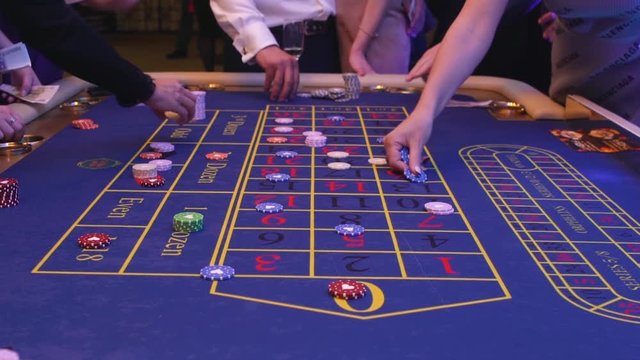 A table with a roulette in a casino. The croupier gives out a prize. Gambling for money. People make bets on roulette. Underground Casino