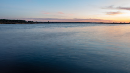 colorful sunset over the sea lake with dark red clouds