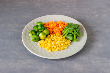 Plate with cabbage, carrots, corn and spinach. Healthy eating.
