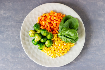 Plate with cabbage, carrots, corn and spinach. Healthy eating.