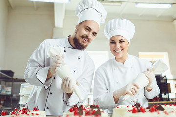 Confectioners with a bag for the cream will decorate the cake.