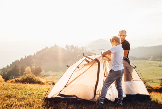 Father and son installing tent on forest glade.Trekking with kids concept image