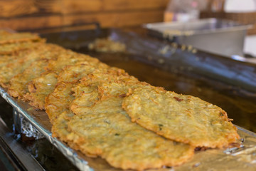 Potato fritters on a big pan, festival fast street food.  Cooking and Selling Fresh langos on the street