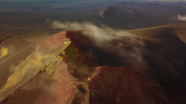 Drohnenaufnahme von Wolken die &uuml;ber einen roten Vulkan am Tolbachik in Kamtschatka ziehen