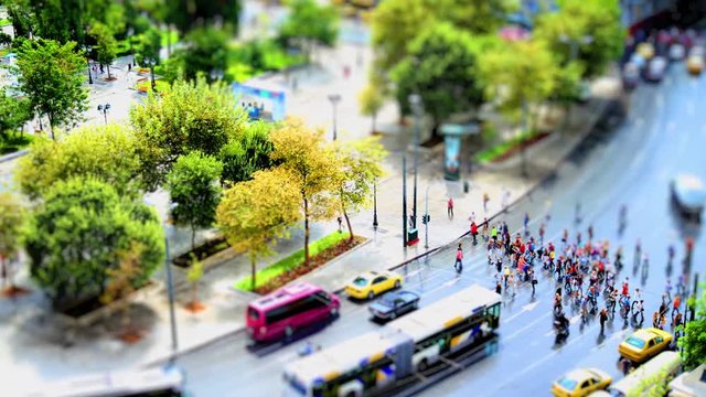 Miniature effect time lapse video with a tracking shot of a street in the central square of Athens (Syntagma) in Greece during daytime with people crossing the high street.