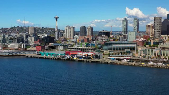 Aerial tracking, drone shot, panning around the coast, skyscrapers in the background, in downtown Seattle, above Elliot bay, on a sunny day, Washington state, USA