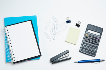  White office desk with calculator, notepad and sticker. Stationery on white background