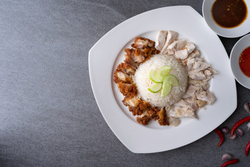 Hainanese chicken rice or rice cooked in chicken broth in the white dish.