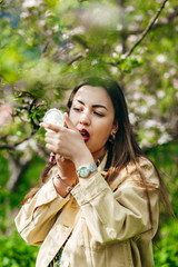 Young beautiful hipster happy woman doing make-up in garden, spring trend