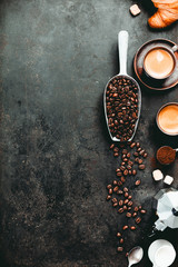 Coffee espresso in dark cups, coffee beant, ground coffee, brown sugar, milk, croissants, capsules.