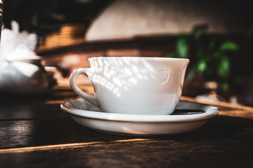 White tea cup  with open shadow on rustic wooden table.  Cozy tea time atmosphere.