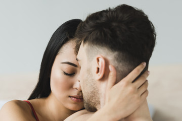 Fototapeta premium beautiful, pensive asian woman with closed eyes embracing boyfriend