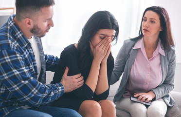 Psychologist comforting sad female patient in office