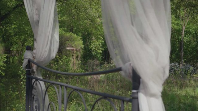 A focusing shot of waving curtins of a four poster bed in the forest