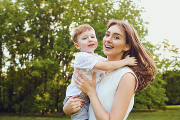 Mother and child play hugging in the park. 