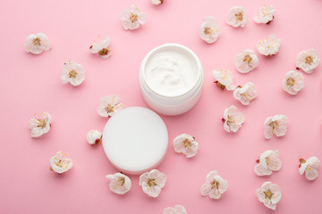 Cosmetic container with apricot blossoms on a pink background. Blank label for branding mock-up. Natural beauty product concept. Spa natural skin care products Flat lay style.