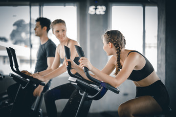 Fototapeta na wymiar Group of people biking in the gym, exercising legs doing cardio workout cycling bikes. Couple in a spinning class wearing sportswear. Fitness, Healthy, Sport, Lifestyle concept.